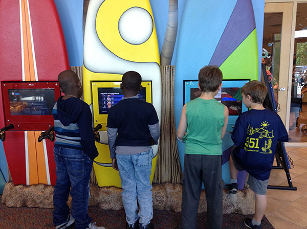 Kids playing the surfboard arcade games while they wait